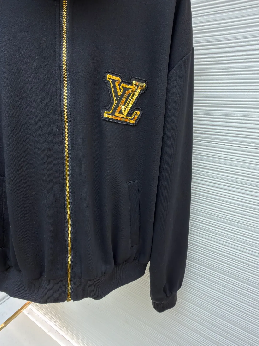 LOUIS VUITTON stand-up collar ribbed hem long-sleeved logo decorated jacket ●Original version: Purchased and developed at 25899 ●Item number: 1682404-B25 ●Fabric: cotton fabric ●Technology: knitted production ●Color: black ●Version: fitted version ●Weight: about 990 grams ●Size: S-M-L-XL ●Description: This Louis Vuitton stand-collar zipper jacket is made of high-thread-count cotton-elastic blended fabric, which has been treated with enzyme washing process. The fabric is soft to the touch and has good wrinkle resistance and elasticity. The body has a delicate matte texture. The LV logo on the chest uses a combination of gold thread embroidery and patchwork. The embroidery uses interlaced flat stitch and chain stitch techniques. The stitch density reaches 12 stitches per centimeter. The edges are overlocked and the pattern is three-dimensional and not easy to fall off. The jacket adopts a stand-up collar design, and the collar ribs are made of spandex blended material, which has been shaped to ensure that it will not loosen after long-term wear. The front is equipped with a custom brass zipper, and the zipper teeth are polished and gold-plated, making it smooth, wear-resistant and of high-quality texture. The side seam pockets are welted, and the seams are reinforced with double-needle sewing. The ribbed edges of the cuffs and hem are woven with high-elastic yarns of the same color. The shoulders are seamlessly spliced ​​with natural shoulder shapes. The overall craftsmanship combines the brand's classic elements with practical design, fully demonstrating the production level of high-end clothing. The overall wiring is straight and delicate, the fabric is comfortable and soft, and the color is consistent without color difference. It can be matched with the same style to create a fashionable look and control various occasions. Customized accessories, complete with three standards, same style for men and women!